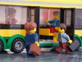 Two Lego businessperson minifigures who are holding suitcases getting on to a bus