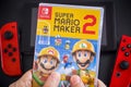 A man holding a Super Mario Maker 2 video game in plastic case for the Nintendo Switch console