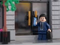 Tambov, Russian Federation - July 26, 2023 A Lego businessman minifigure standing in front of the doors of a bank and answering
