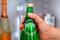 Close-up of woman hand taking out bottle with Perrier water from fridge