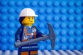 Lego miner with pickaxe against blue baseplate backgrounds