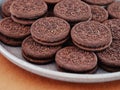 Heap of Oreo cookies on a gray plate. Brown background