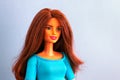 Portrait of Barbie doll with brown hair against blue background