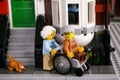 Lego senior couple and ginger cat near his house in the street. Man sits in wheelchair, woman helps him