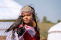 Almaty / Kazakhstan - 09.23.2020 : A little girl in Kazakh national dress holds a Balaban Falcon in her arms