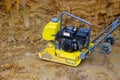 Tamping machine preparation of the ground by vibratory plate compactor in construction rammer in foundation pit for construction Royalty Free Stock Photo