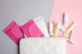 Tampons, pads and bag on color background