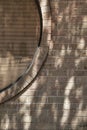 Tan brick wall with section of circular window covered by blinds