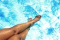 Tan golden legs of young woman and feet painted nails having suntan at swimming pool Royalty Free Stock Photo