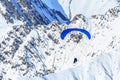 Tandem paragliders soaring against snowy mountain peak. Extreme prarglide winter flight