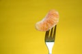 Tangerine skewered on fork isolated on yellow background