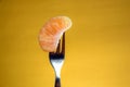 Tangerine skewered on fork isolated on yellow background