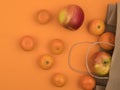 Tangerines and apples in a ecological paper bag. Orange background