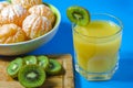 Tangerines and kiwi. The juice is poured into a glass. Blue background, close-up