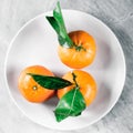 Tangerines with leaves on plate - citrus fruits and healthy eating flatlay concept