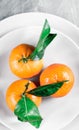 Tangerines with leaves on plate - citrus fruits and healthy eating flatlay concept