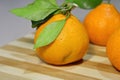 Tangerines with leaves on a wooden board on the table.