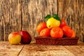 Tangerines and lemon in a wicker basket, red apples lie on an old wooden table Royalty Free Stock Photo