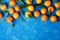 Tangerines or mandarins with green leaves on rustic blue table from above in flat lay style.