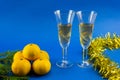 Tangerines, a spruce branch, glasses of wine and yellow tinsel with copy space Royalty Free Stock Photo