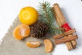 Tangerines, walnuts, cinnamon sticks and spruce branch. Lying on a piece of linen. Against the background of white painted boards