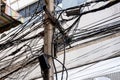 Tangle of Electrical cables and Communication wires on electric pole with building in the city Royalty Free Stock Photo