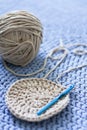A tangle of gray yarn lies on a blue knitted carpet