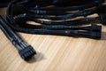 Tangled black computer cables lying on a brown wooden table