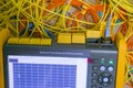 A tangled bundle of fiber optic wires is located next to the cable analyzer. Computer measuring device. Optical signal level