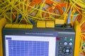 A tangled bundle of fiber optic wires is located next to the cable analyzer. Computer measuring device.  Optical signal level Royalty Free Stock Photo