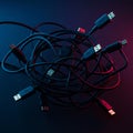 A tangled bundle of various USB cables is displayed against a dark background. The Royalty Free Stock Photo