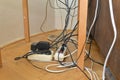 Tangled cables in the extension cord. Messy cables. Cables tangled on parquet flooring.