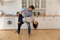 Romantic millennial couple dance on warm floor at home kitchen