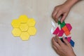 Tangram hexagon flower colored child geometric puzzle piece with childs hands moving pieces