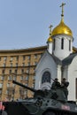 Tank against background of white chapel. Military equipment drives through empty streets of city. Preparations for Victory Parade