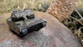 Tank plastic toy laying on stone. Military vehicle moving through the stone. Simple cheap toys for children.