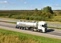 Tank truck MAN driving on highway. `B.S.A.T.` specifics of the truck transportation of liquid goods. Metal chrome cistern tanker