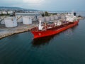 Tanker ship refueling at an oil terminal with storage silo's in the port, aerial view Royalty Free Stock Photo