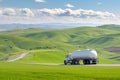 tanker truck driving past green rolling hills Royalty Free Stock Photo