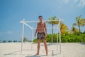 Tanned attractive sexy handsome young man in swimming wear at tropical beach at island luxury resort Royalty Free Stock Photo