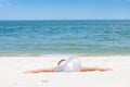 Tanned beautiful woman in hat lying on the beach sand