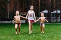 Tanned cheerful children run barefoot on the green grass on vacation in the hot summer