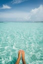 Tanned feet of a woman sticking out of the ocean in the Maldives