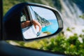 Tanned female hand in the car side view mirror. Blue mediterranean sea and white rocks landscape in background Royalty Free Stock Photo