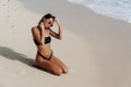 tanned girl in black swimsuit and sunglasses posing on sandy beach Royalty Free Stock Photo