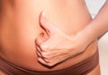 A tanned girl holds her hands to her stomach. IVF concept, pregnancy, digestion, health of the female reproductive system.