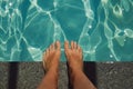 tanned legs against the background of clear water in the pool. summer vacation under the sun. background for the design Royalty Free Stock Photo