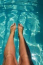 tanned legs against the background of clear water in the pool. summer vacation under the sun. background for the design Royalty Free Stock Photo