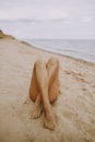 Tanned legs of a girl on beach with sand on smooth skin. Beautiful authentic and unusual image. Young woman relaxing on seashore Royalty Free Stock Photo