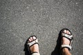 Tanned male legs in hiking sandals on the asphalt on a sunny day.